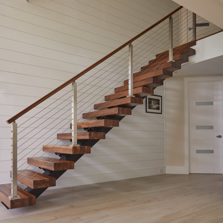 Floating stairs with walnut treads and stainless steel cable railing