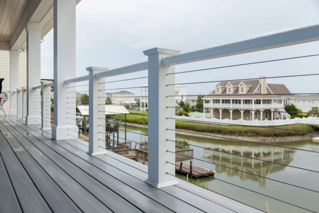 DriveTite cable railing kit with traditional white, wooden posts on a scenic deck overlooking a residential bay