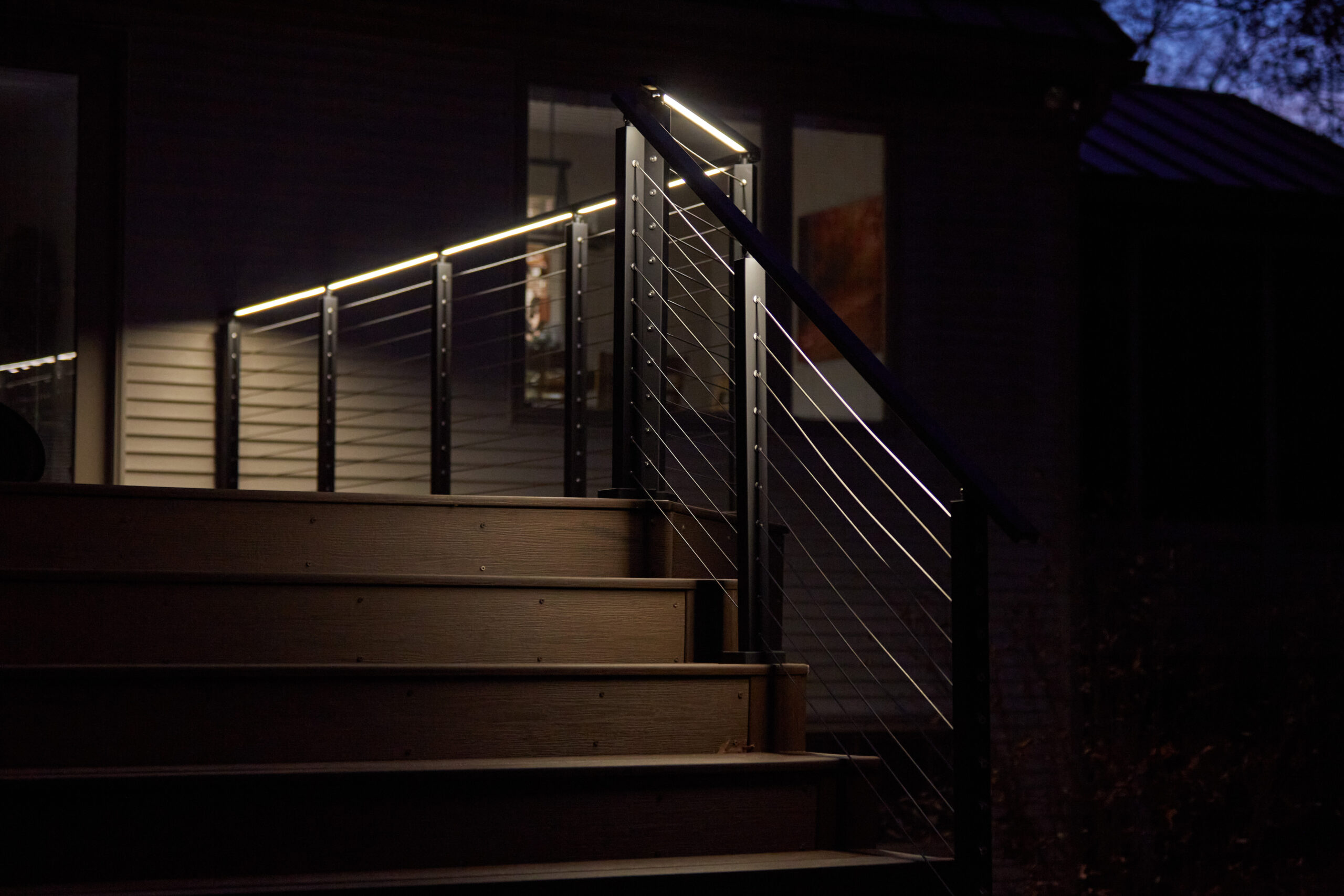 Cable railing with LED under-lit handrail on a deck at night