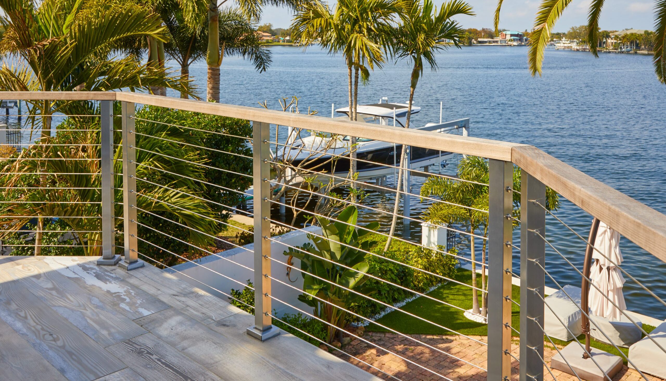 Wood handrail on a sleek cable railing system overlooking a coastal bay