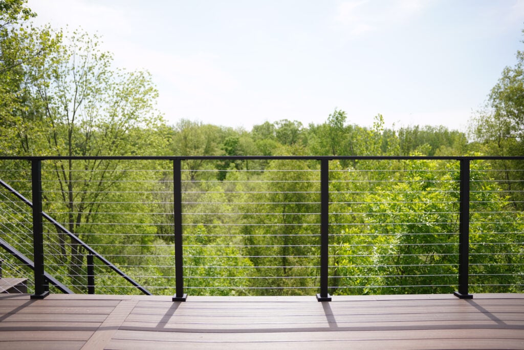 DIY cable deck railing on a simple deck overlooking a forest